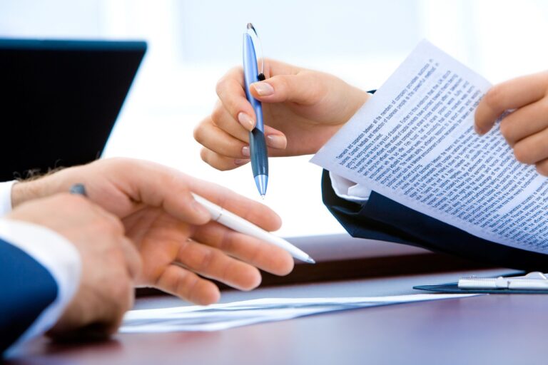 Close-up of hands reviewing an insurance contract, signifying scrutiny for instances of bad faith in insurance dealings. A bad faith insurance lawyer can help.