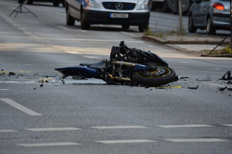 Overturned motorcycle on the road with visible damage, depicting the aftermath of a crash